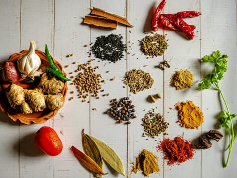 Whole and ground spices including cinnamon, dried red chillies, turmeric, chilli powder, curry powder, cumin, peppercorns and cardamom.