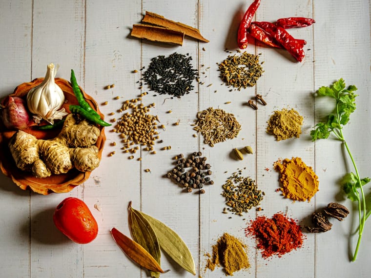 Whole and ground spices including cinnamon, dried red chillies, turmeric, chilli powder, curry powder, cumin, peppercorns and cardamom.